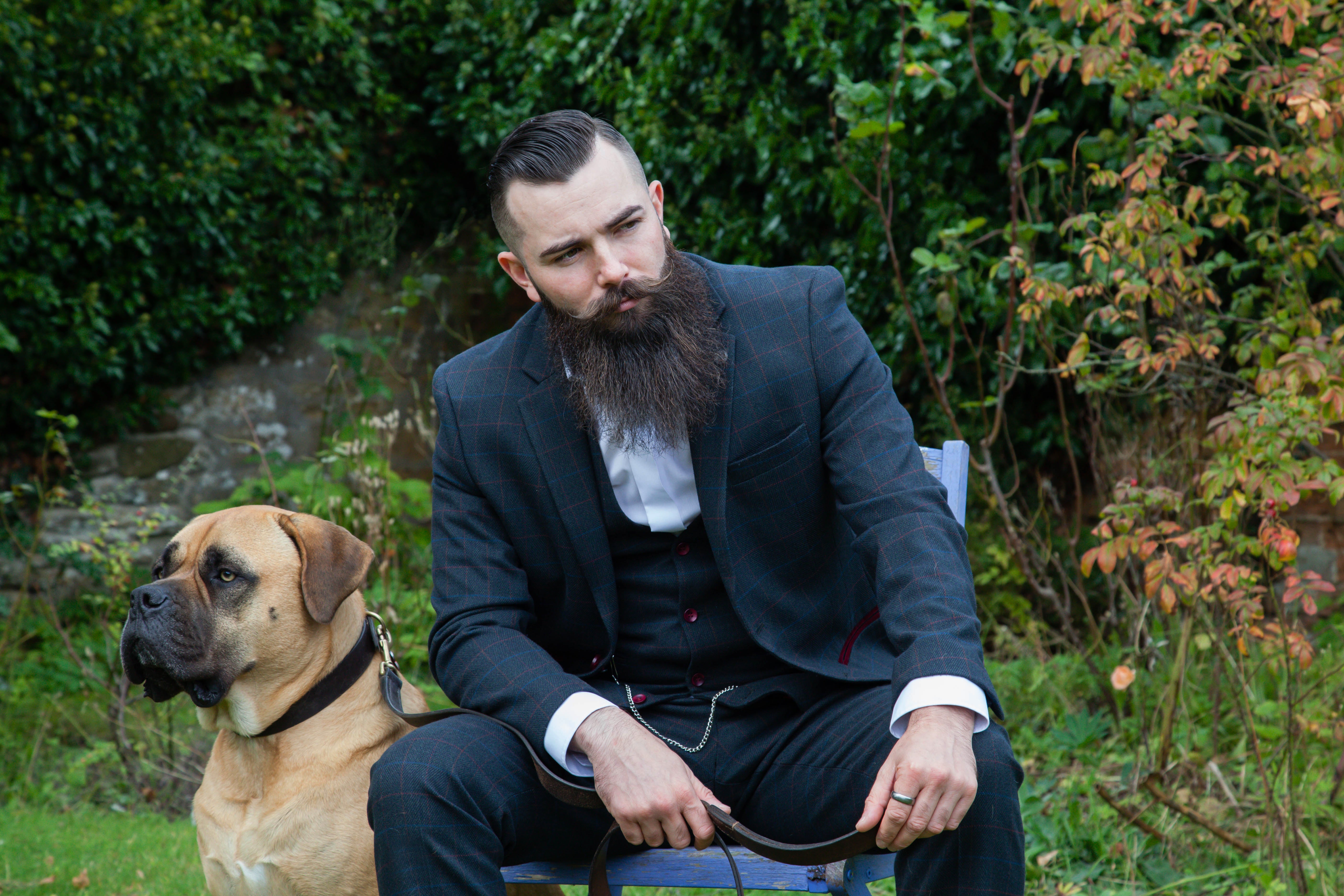 A bearded man sitting on a chair outisde